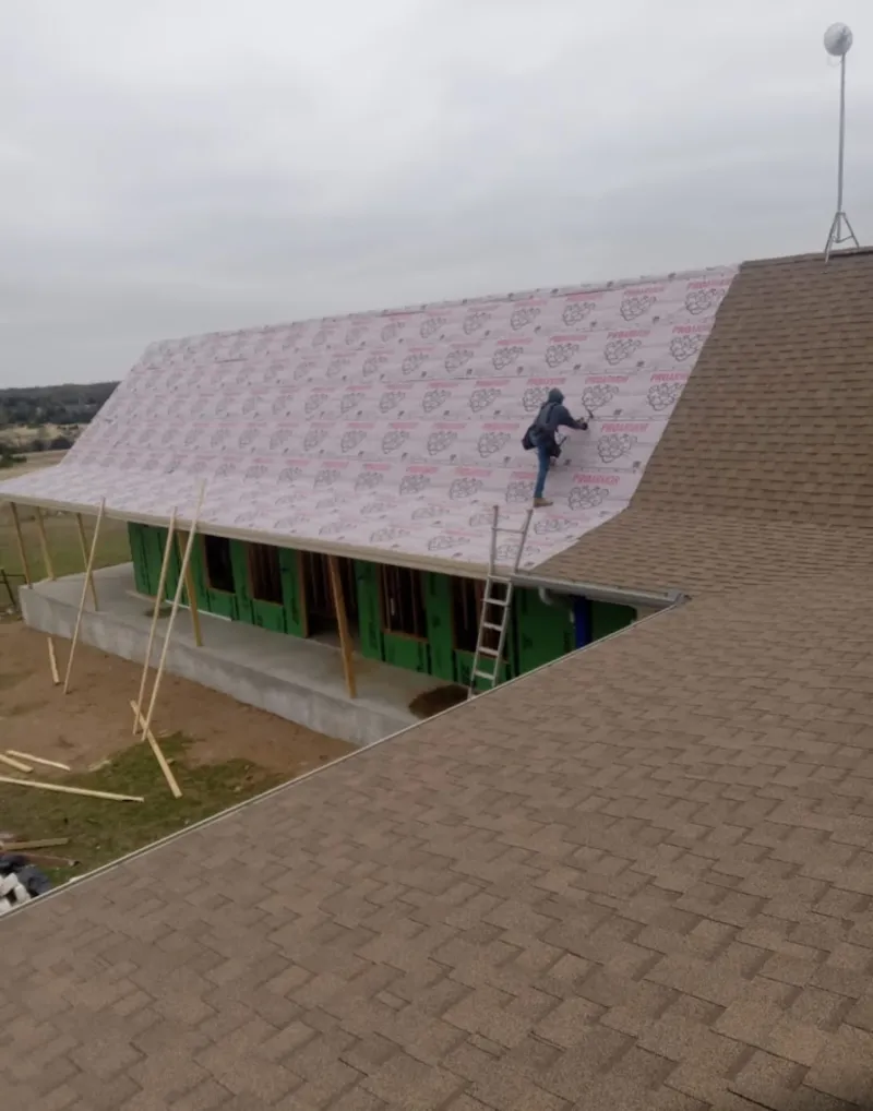 Worker preparing underlayment for a metal roof installation in Pawtucket